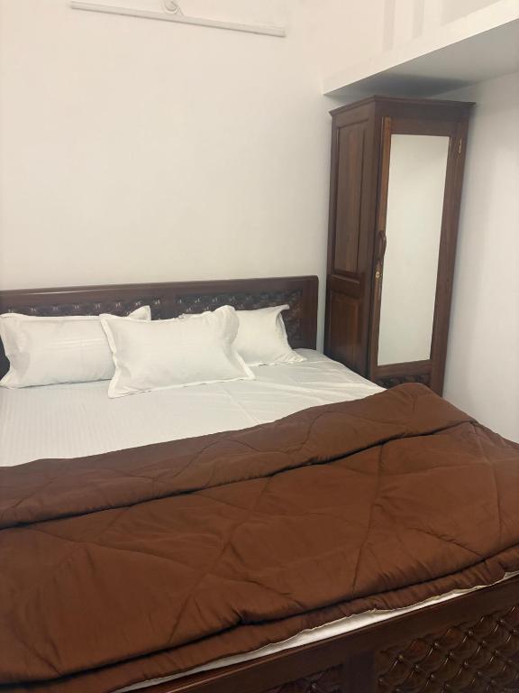 a bed with white sheets and a wooden headboard at Varson Stay in Pondicherry