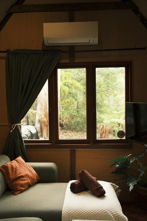 a bedroom with a bed and a window and a couch at Rancho Relaxo Tiny House - in town sanctuary in Margaret River Town