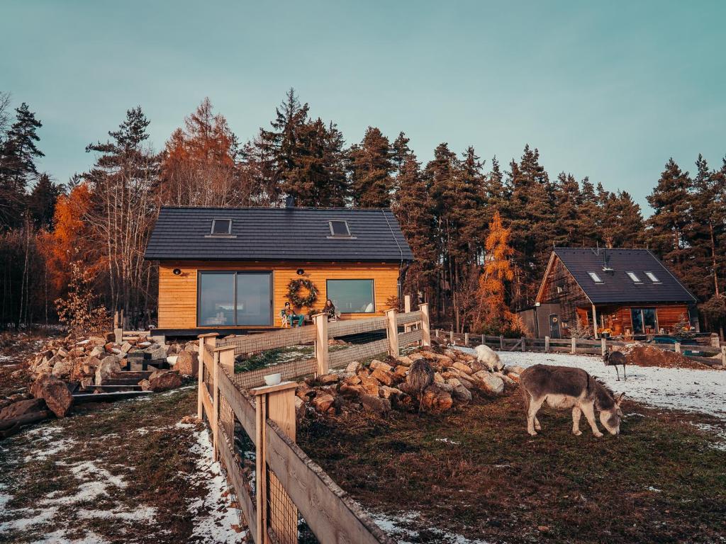 a house with a cow standing in front of a fence at Cozy Chalet in Smolné Pece