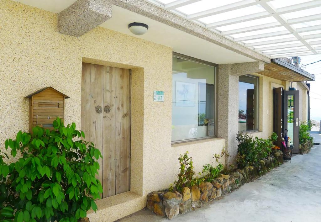 une maison avec une porte en bois sur le côté dans l'établissement Jiufen Breeze 九份惠風民宿ｌ6人包棟小屋, à Jiufen