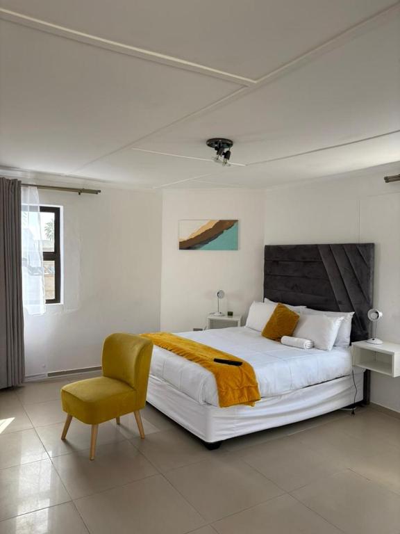 a bedroom with a large bed and a yellow chair at Suuka Guest House in Walvis Bay