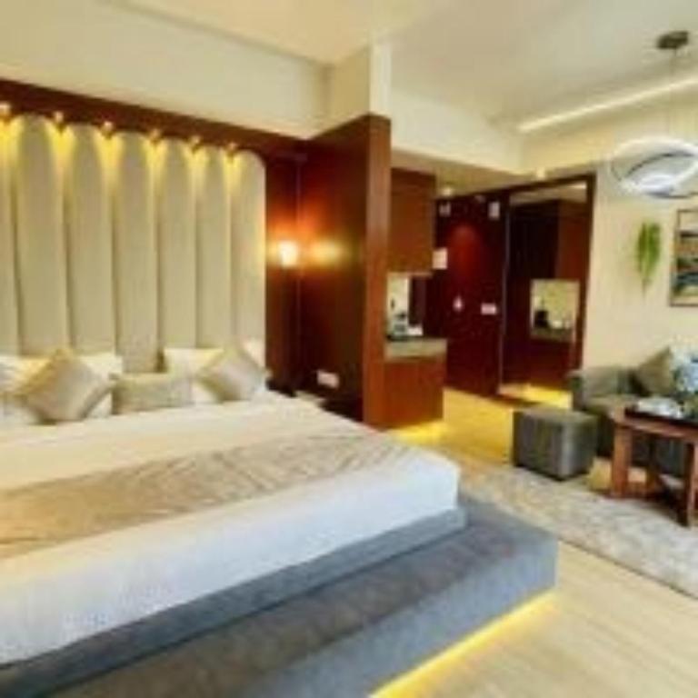 a bedroom with a large bed and a living room at Hotel The Grace Residency - Near Hotel Hyatt ,DLF MyPad, Gomtinagar, Lucknow in Lucknow