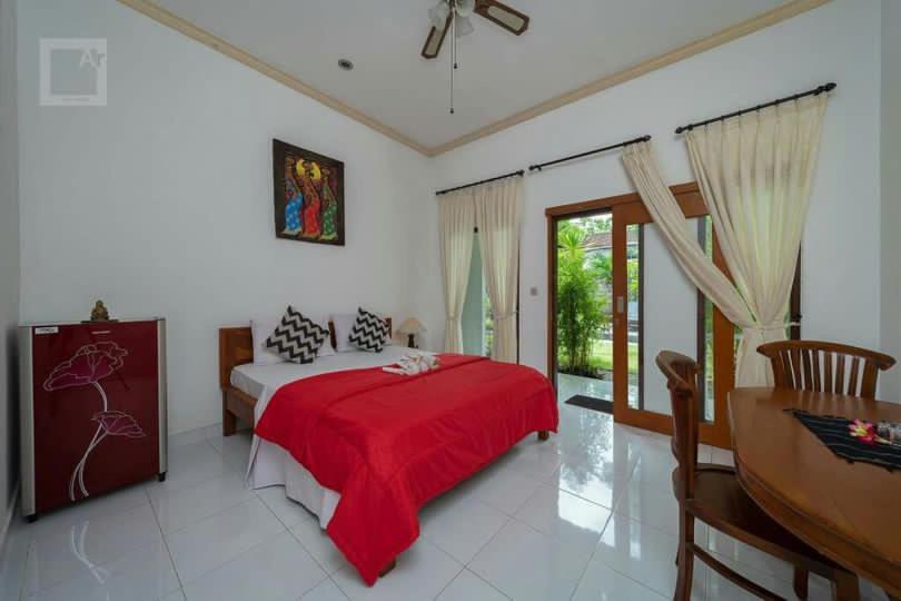 a bedroom with a bed with a red blanket at Pondok tulamben in Karangasem