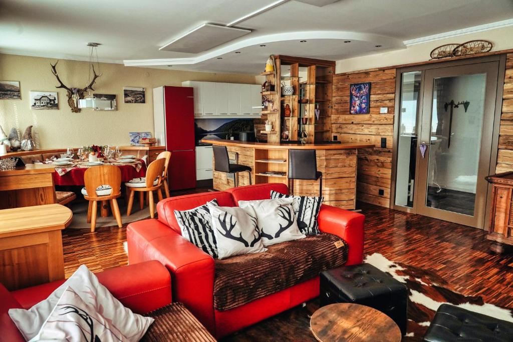 een woonkamer met een rode bank en een keuken bij ALPENLOFT Gerlitzen Ski in - Ski out! in Kanzelhöhe