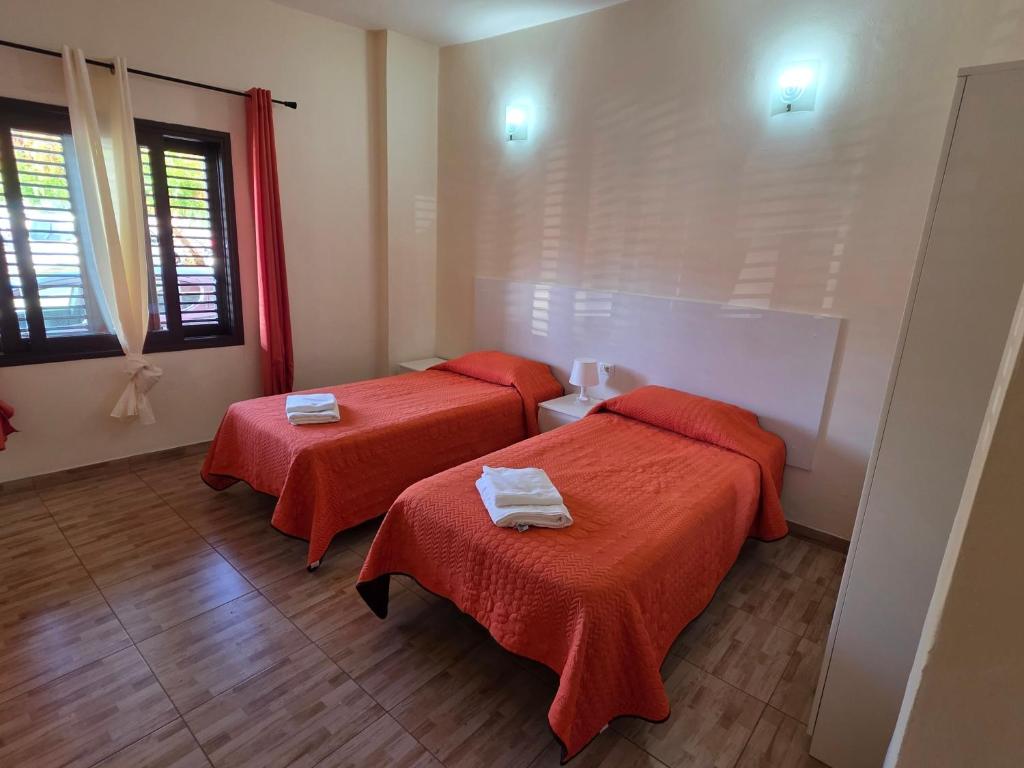 twee bedden in een kamer met rode lakens bij apartamentos la villa 3 in San Sebastián de la Gomera