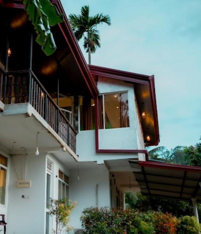 a white building with a balcony and a porch at Rainforest Holiday Inn in Deniyaya