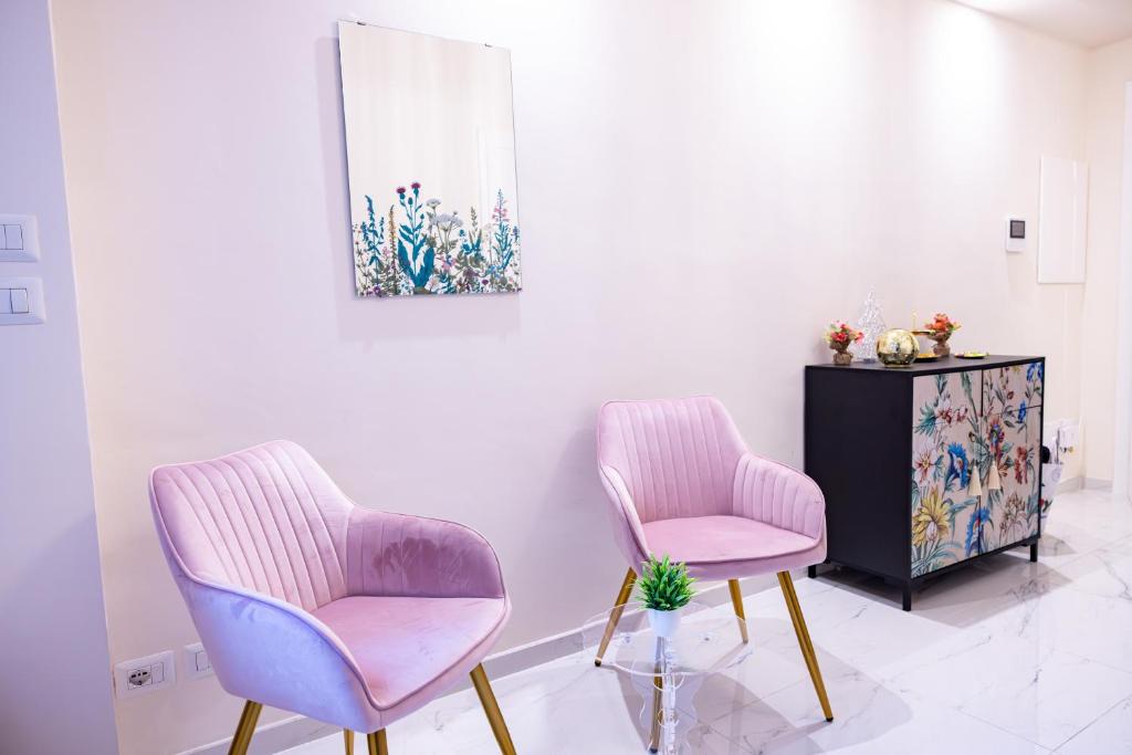 zwei rosa Stühle und ein Schrank in einem Zimmer in der Unterkunft Ginevra Luxury Taormina in Taormina