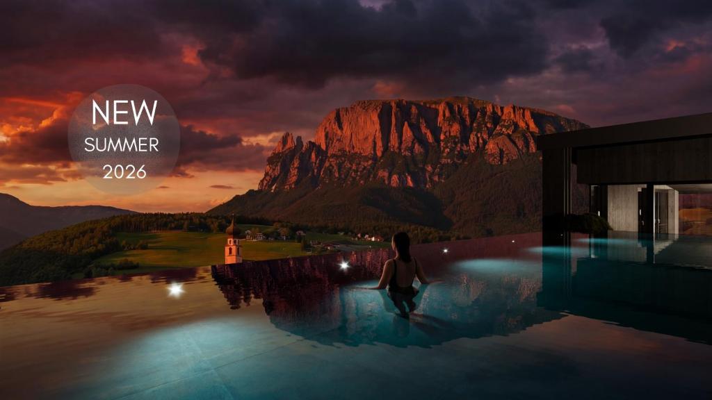 a woman standing in a pool with a mountain at Gartenhotel Völser Hof - Adults Only in Fiè
