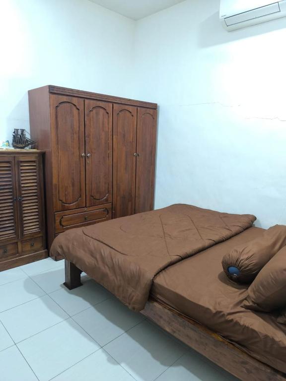 a bedroom with a bed and a wooden cabinet at Nani Homestay in Kampong Bukit Kuang