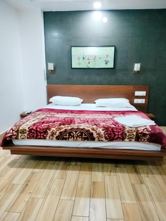 a bedroom with a large bed with a wooden headboard at Hotel Allseasons in Roorkee