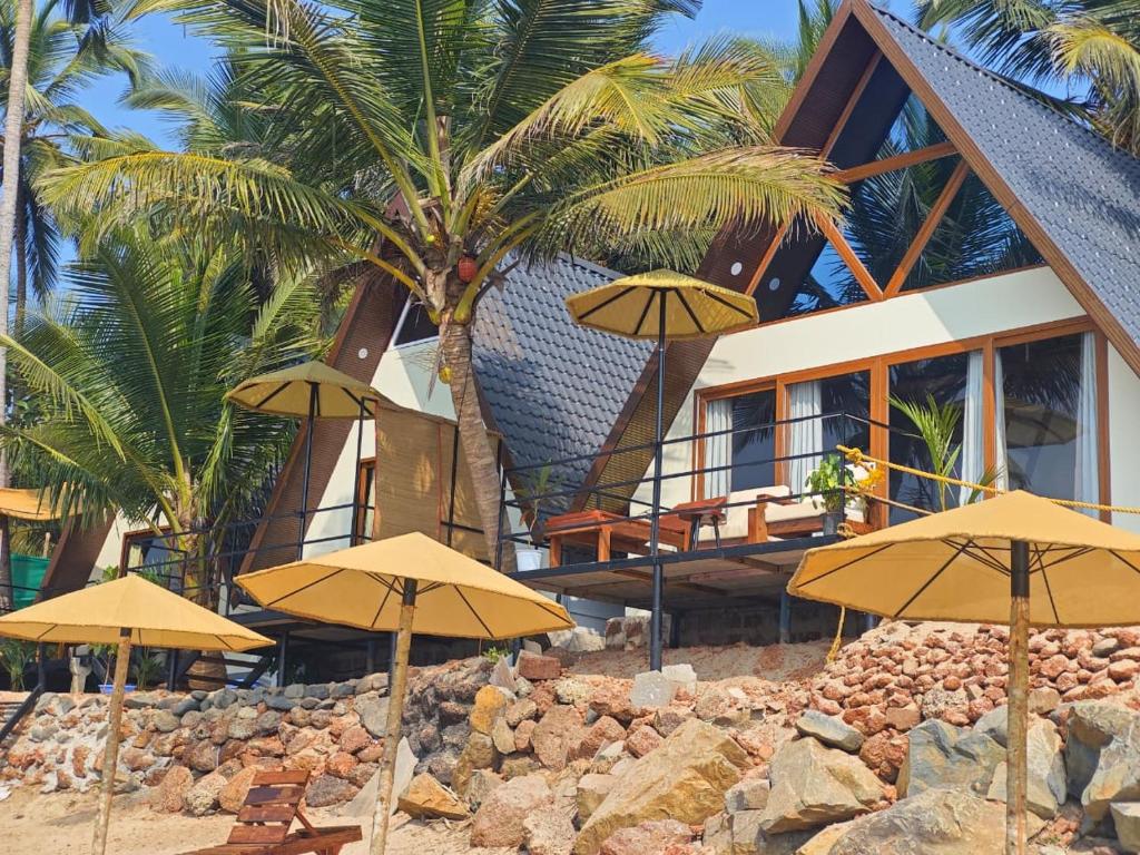 een groep parasols op het strand voor een huis bij Colomb Beach Cottages in Patnem