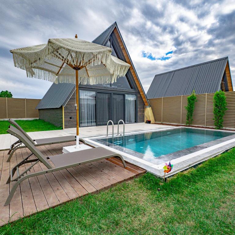 a pool with an umbrella next to a house at Beloris Bungalov in Erenköy