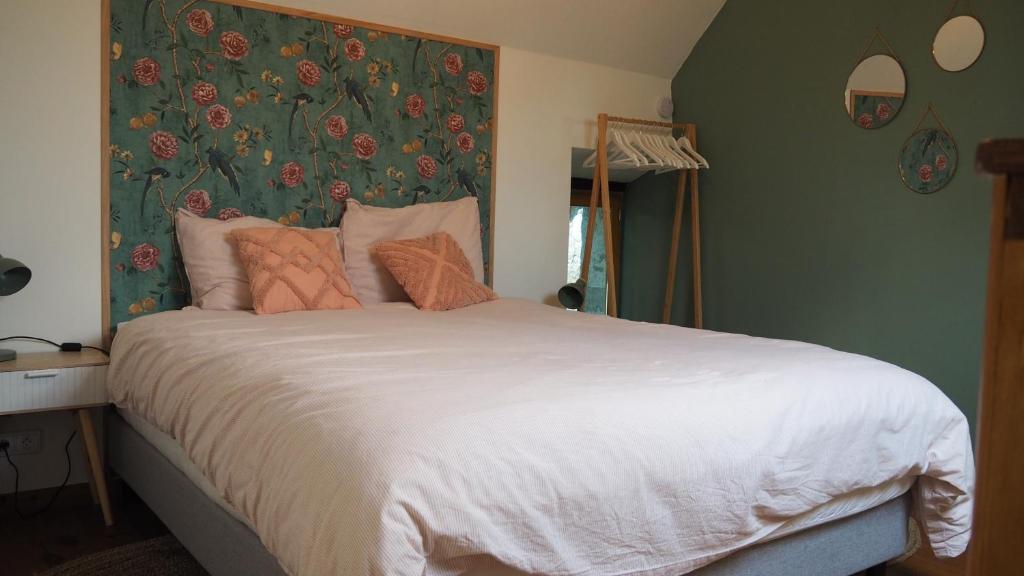 een slaapkamer met een groot bed met een bloemrijk hoofdeinde bij La Vache Bleue in Saint-Pierre-de-Fursac