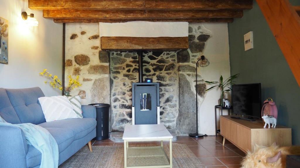 a living room with a blue couch and a stone fireplace at La Vache Bleue in Saint-Pierre-de-Fursac