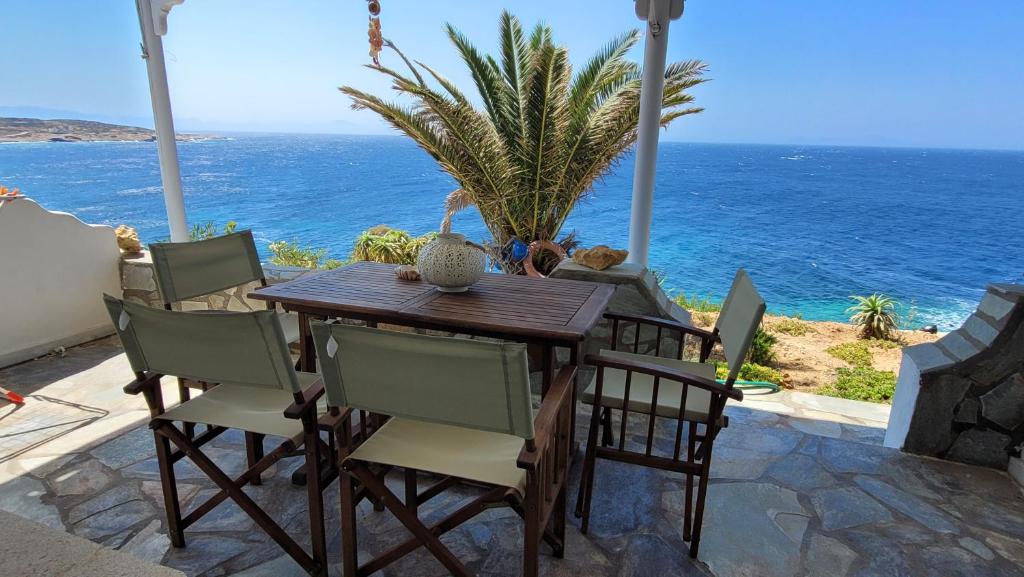 a wooden table and chairs with the ocean in the background at Akrogiali studios in Donoussa