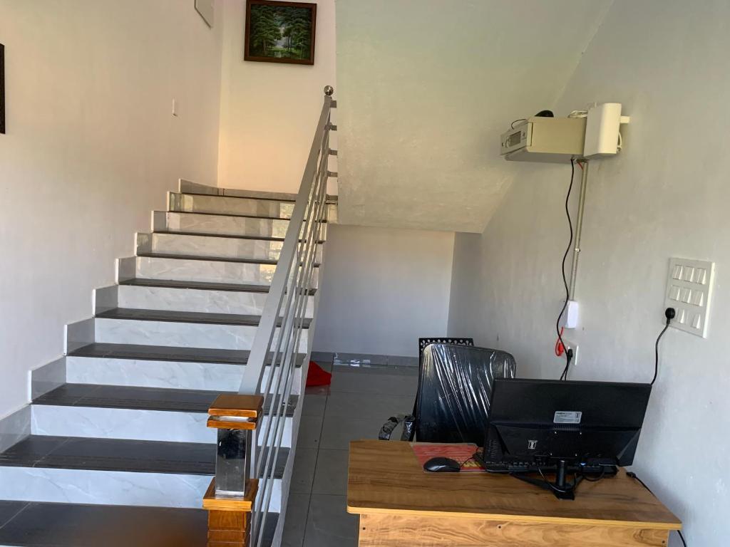 a room with a staircase with a laptop on a desk at Elysian in Mananthavady
