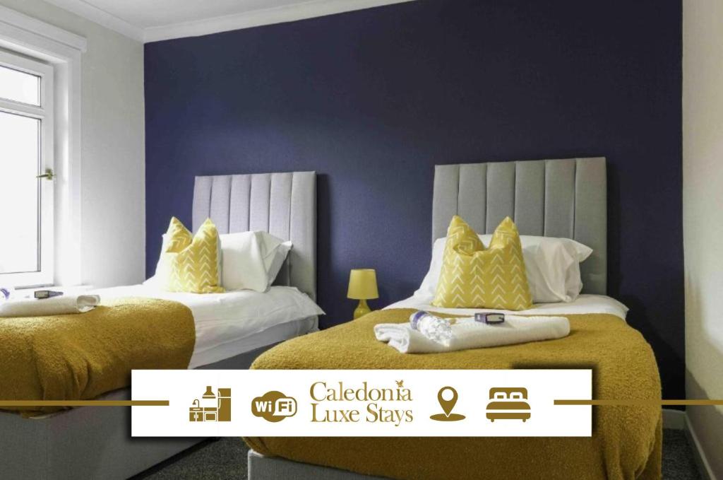 twee bedden in een kamer met een blauwe muur bij 3 BDR House By Caledonia Luxe Stays Short Lets & Serviced Accommodation Bathgate in Bathgate