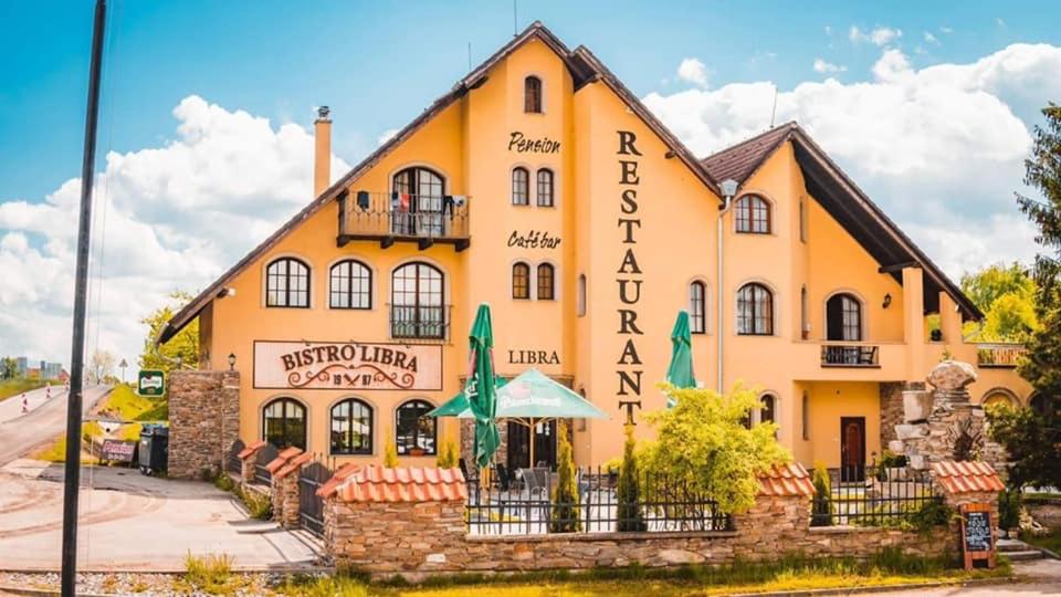 een groot geel gebouw met een bord erop bij Pension Libra in Velešín
