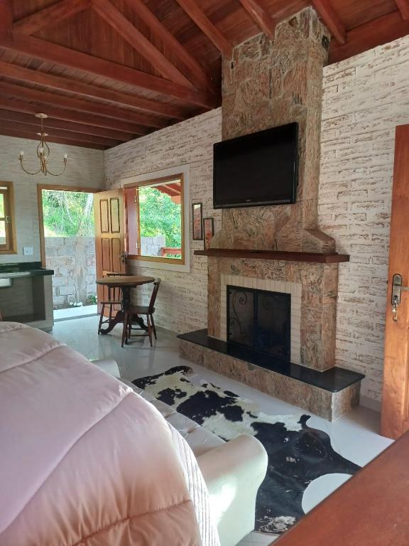 una camera da letto con camino e TV su un muro di mattoni di Chalés Maktub a Camanducaia
