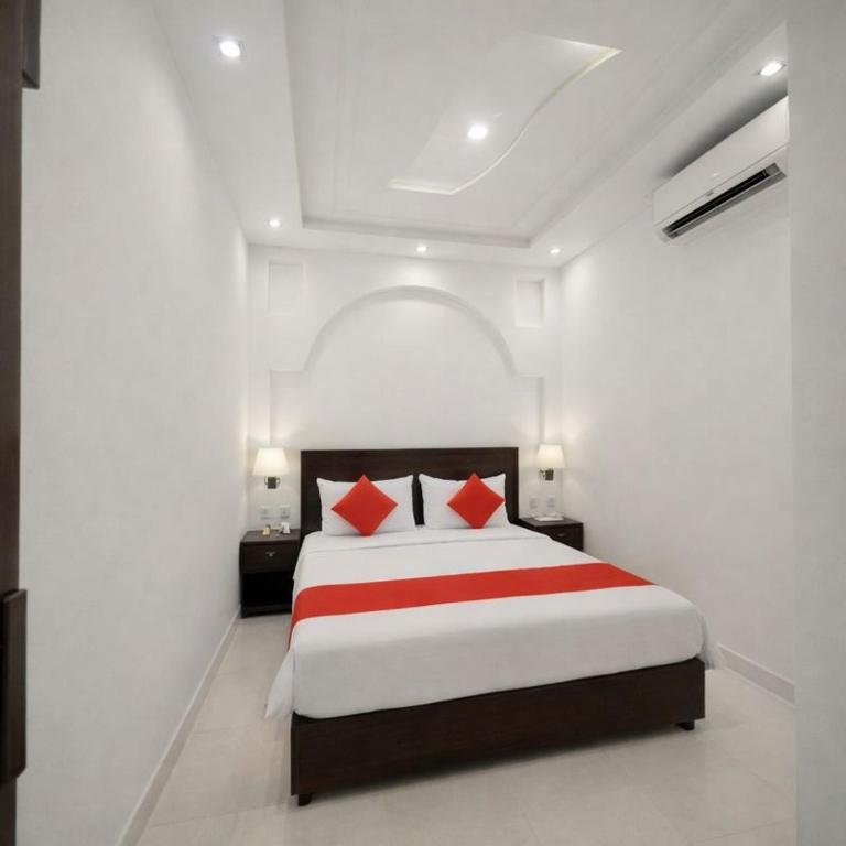 a white bedroom with a large bed with red pillows at Amrit Niwas in Prayagraj