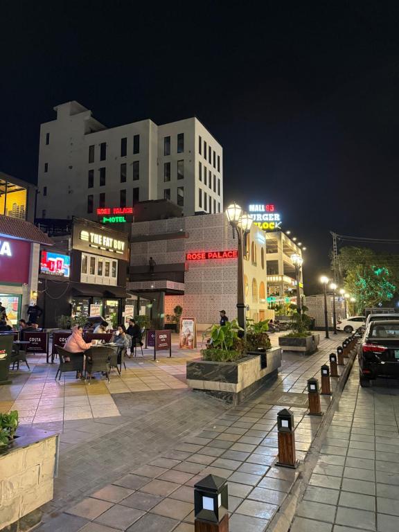 eine Stadtstraße bei Nacht mit Menschen, die an Tischen sitzen in der Unterkunft Rose Palace Hotel, Liberty in Lahore