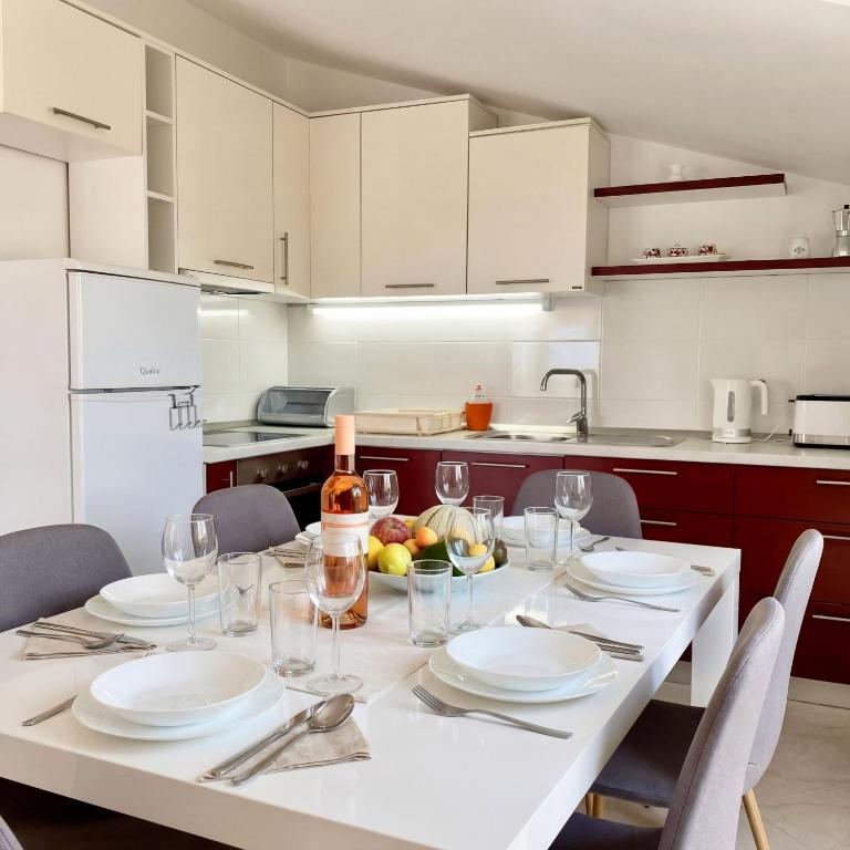 a kitchen with a table with plates and wine glasses at Apartmani Attila in Trogir