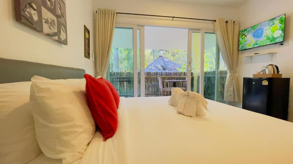 a bedroom with a white bed with red pillows and a window at Beautiful Bungalow 5, Koh Chang in Ban Dan Mai