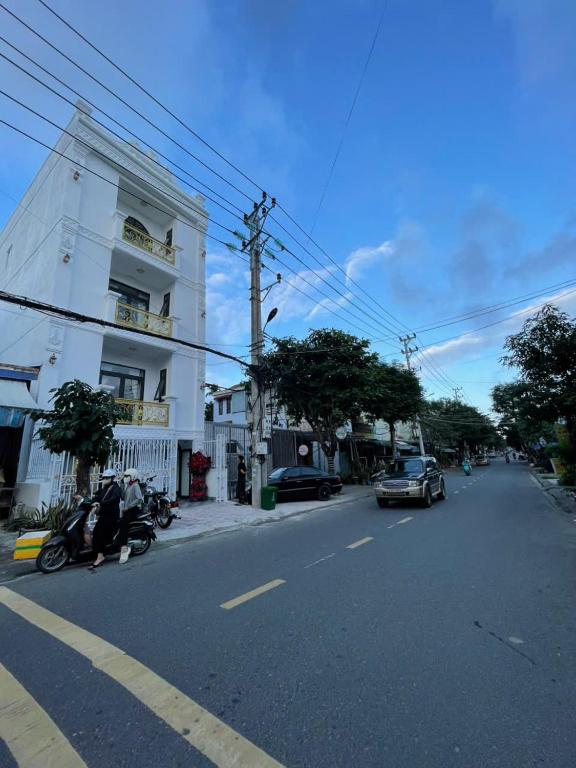 a street with cars and motorcycles parked on the side of a building at LAKSHMI Apartment & Hotel Da Nang in Danang