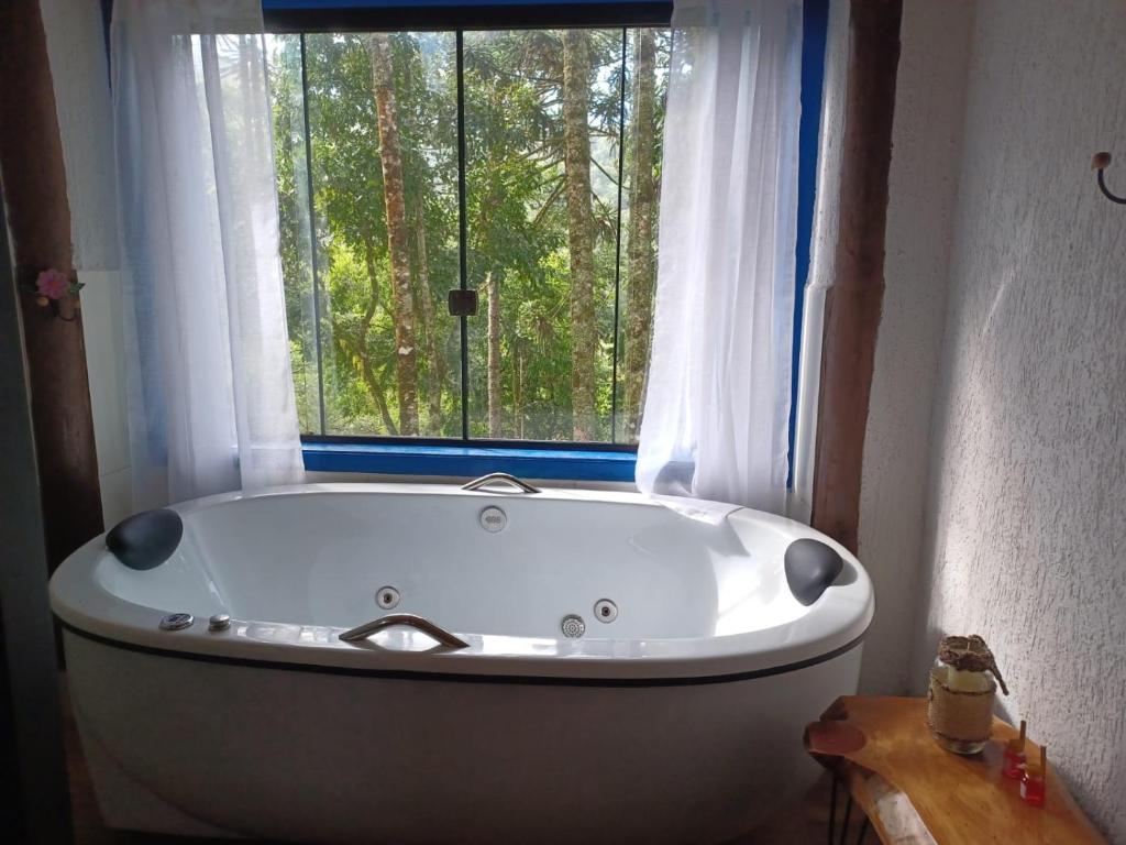 a bath tub in a bathroom with a window at Sopro da Serra Chalé Papagaio in Gonçalves