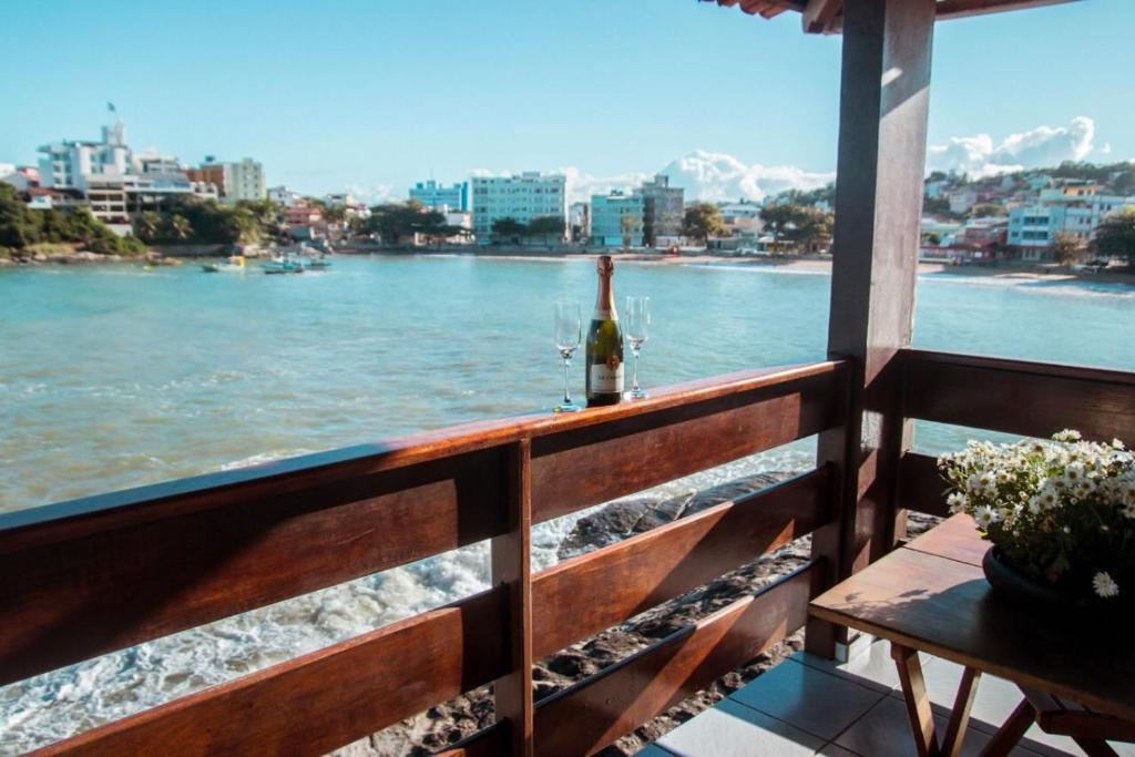 Eine Flasche Wein steht auf einem Balkon mit Blick auf das Wasser in der Unterkunft Pousada Recanto da Pedra in Iriri