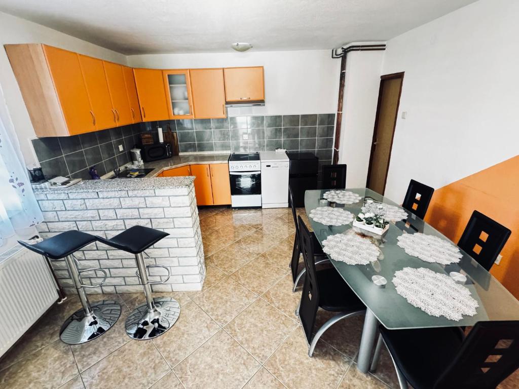 een keuken met een eettafel en een keuken met oranje kasten bij Apartman Šimić in Gračac
