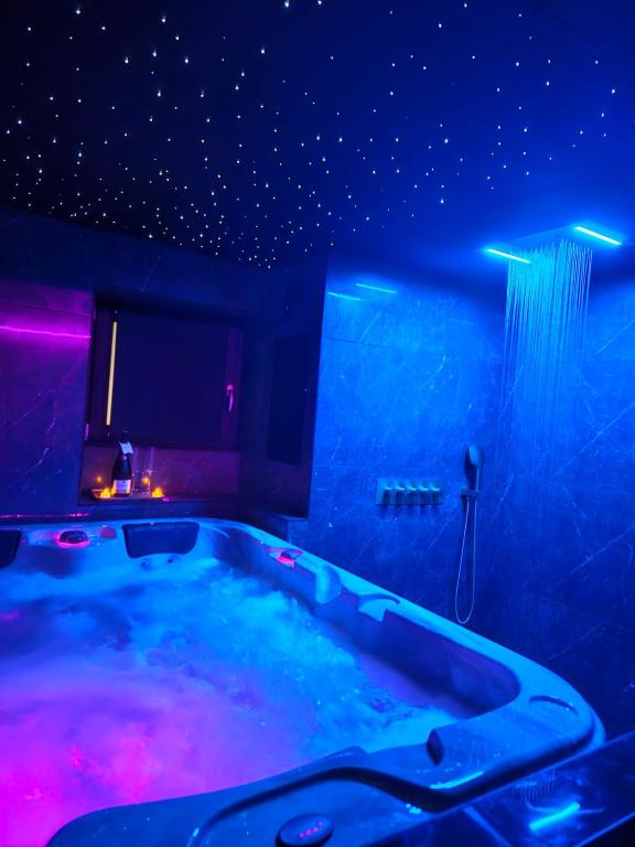 a hot tub in a room with purple and blue lights at Suite romantique avec jaccuzzi - proche des lacs - La secrète room in La Mure