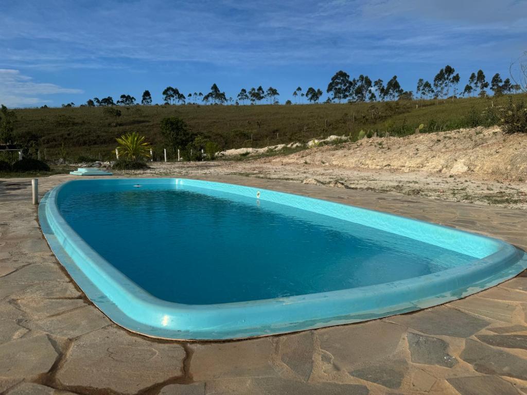 een blauw zwembad dat bovenop een strand ligt bij Sítio Vista da Serra - Carrancas in Carrancas