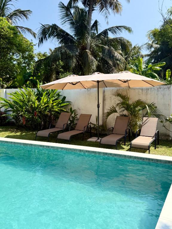 a swimming pool with chairs and an umbrella at Villa Carla Mirissa in Mirissa