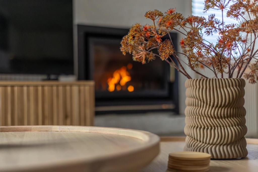 a vase with flowers on a table in front of a fireplace at Beach & Bunker in Hollum