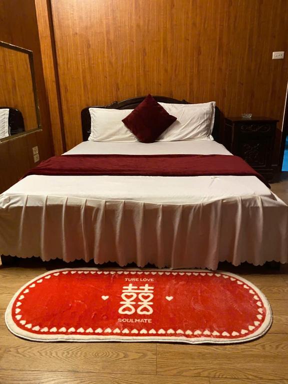 een bed met een rood tapijt op de vloer bij Thanh Lịch Homestay in Hanoi