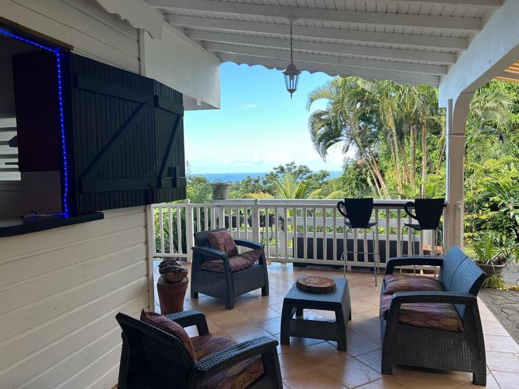 a porch with chairs and a table and a balcony at Studio La Marguerite - Vue mer avec terrasse privée - calme tropical à Deshaies in Deshaies