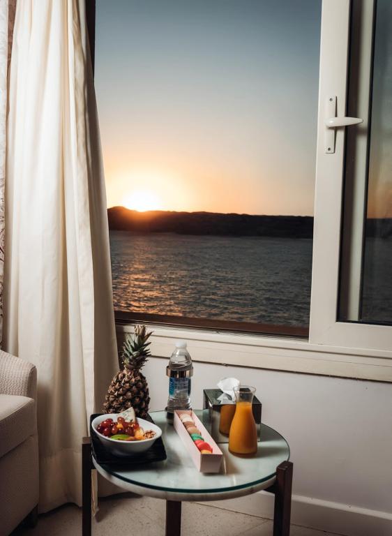 a table with a plate of food on it next to a window at Retac Abu Simbel Nefertari Hotel in Abu Simbel