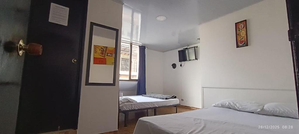 ein kleines Zimmer mit zwei Betten und einem Spiegel in der Unterkunft Hotel Suite Americano in Pereira