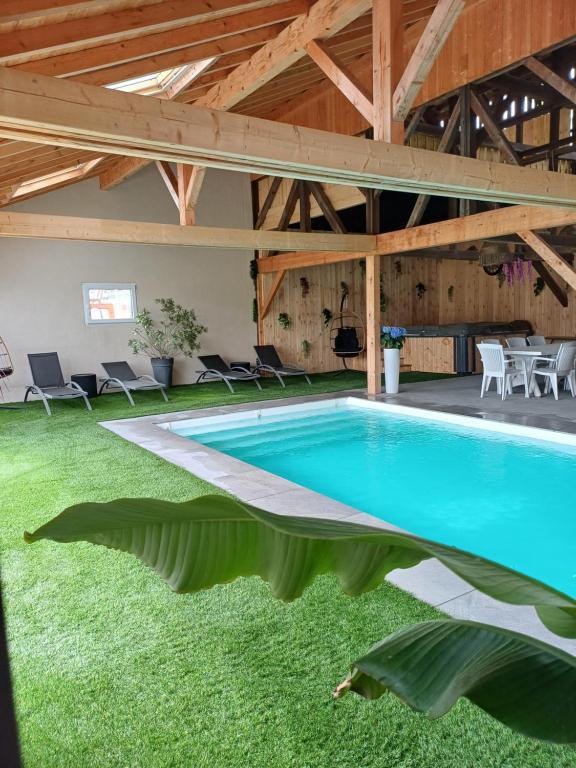 a swimming pool in a building with a table and chairs at Gîtes Kymsourit - Sauna - SPA - proche Europa-Park et Rulantica - Centre Alsace in Sand