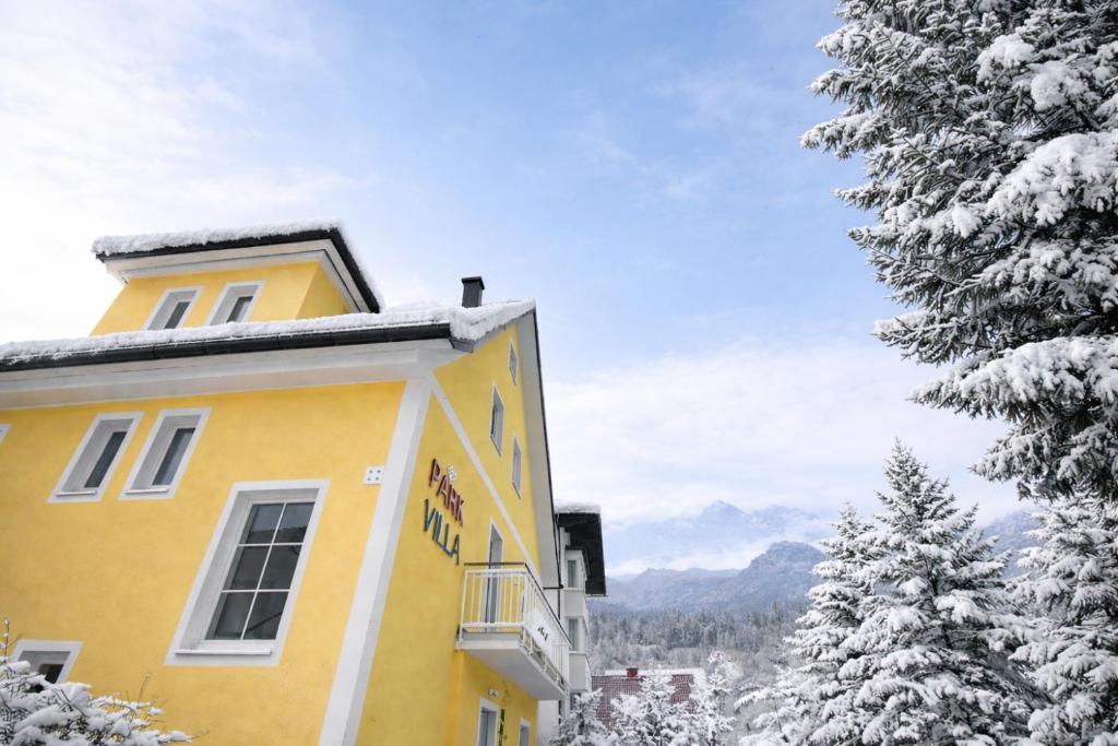 een geel gebouw met sneeuw bedekte bomen en bergen bij Parkvilla Appartements in Bad Hofgastein