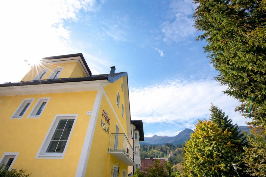 a yellow building with mountains in the background at Parkvilla Appartements in Bad Hofgastein