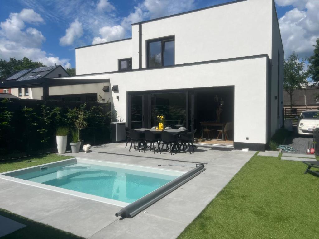een wit huis met een zwembad in de tuin bij Home Terboekt in Genk