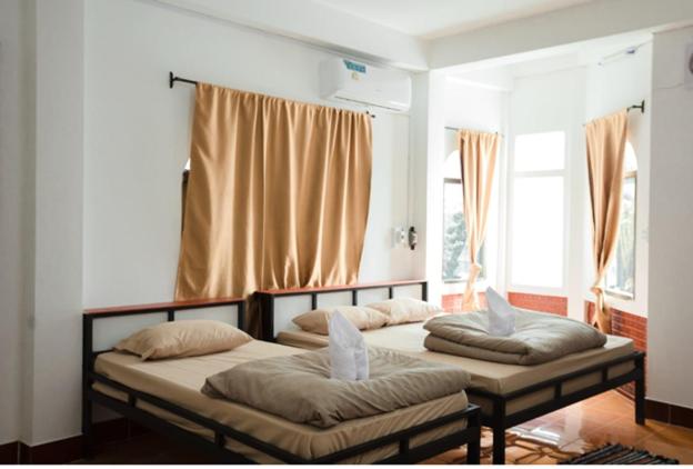 twee bedden in een kamer met twee ramen bij Orlardee hostel in Thakhek