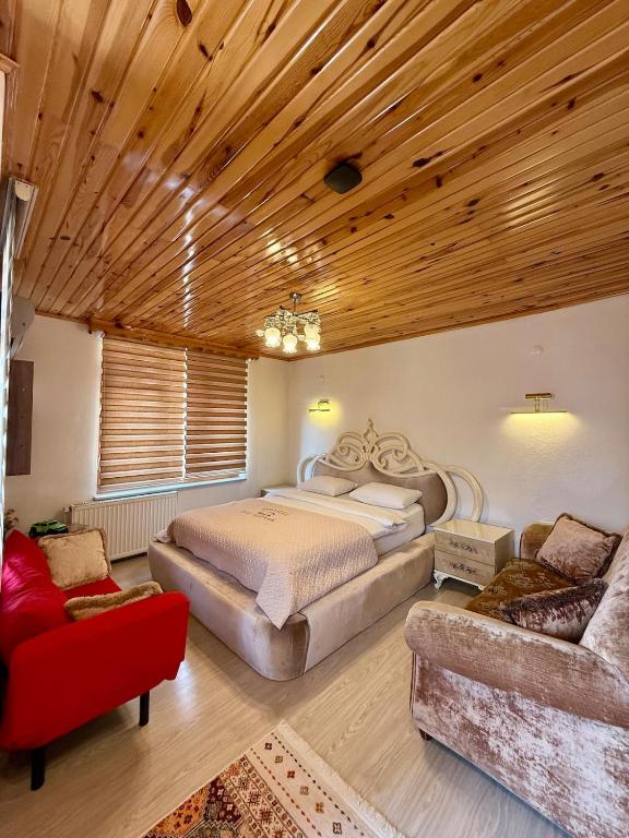 a bedroom with a large bed and a red couch at Isgobya Sumela Monastery 102 in Macka