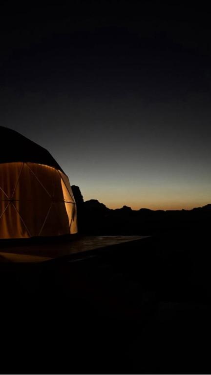 a tent sitting in the desert at sunset at Tariq Camp Wadi Rum in Wadi Rum