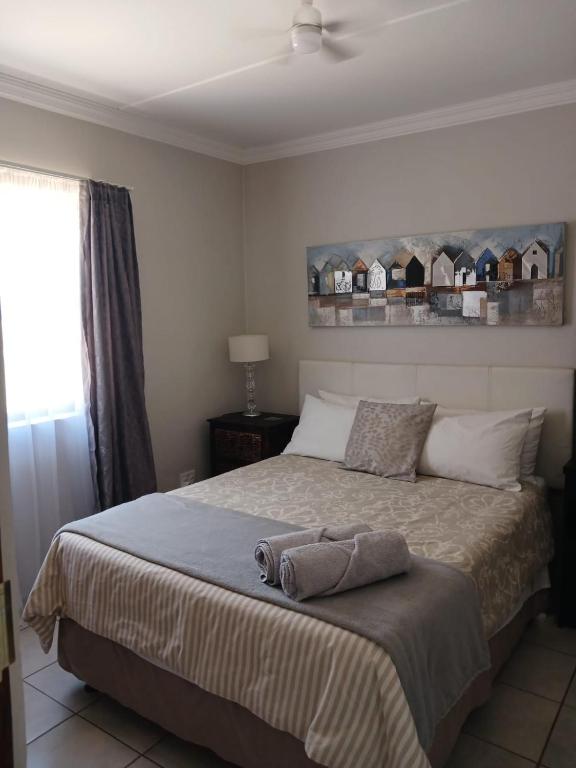 a bedroom with a bed with a blanket and a window at Karoo-Hart in Orania