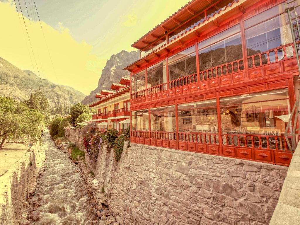 a building on a stone wall next to a river at Sol Ollantay Boutique Hotel in Ollantaytambo