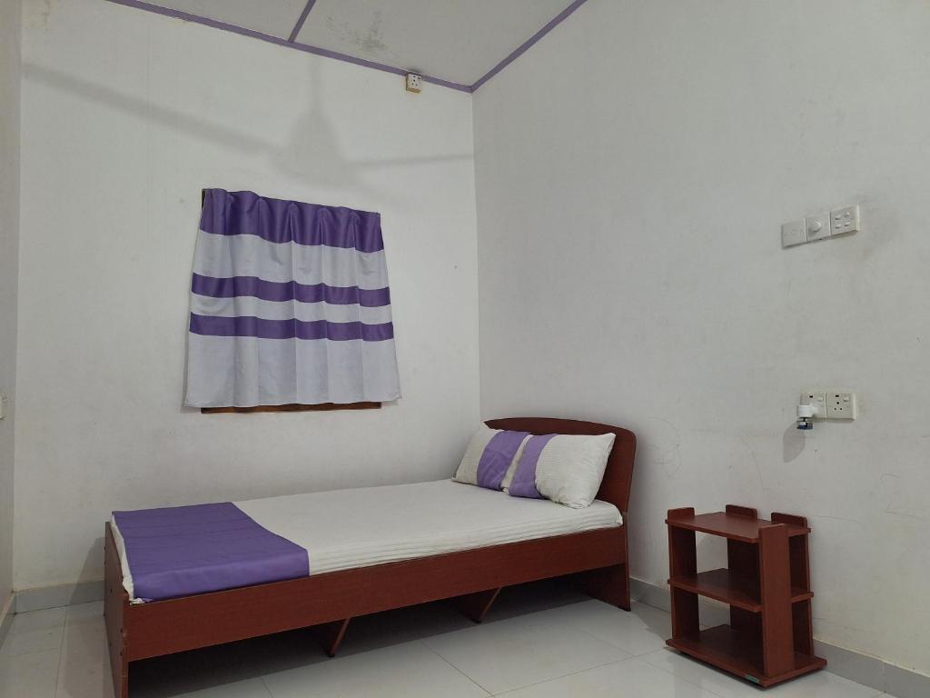 a small bed in a room with a flag on the wall at Priya Villa Homestay in Jaffna