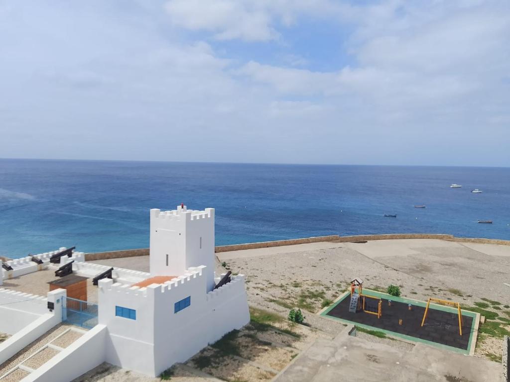a white building with the ocean in the background at Fort Apartments in Vila do Porto